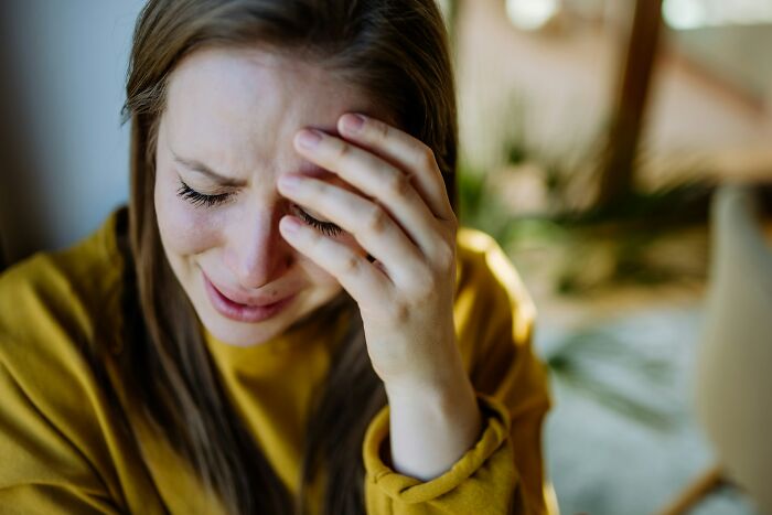 A woman crying with her hand on her forehead, depicting the emotional intensity of some babysitting stories.