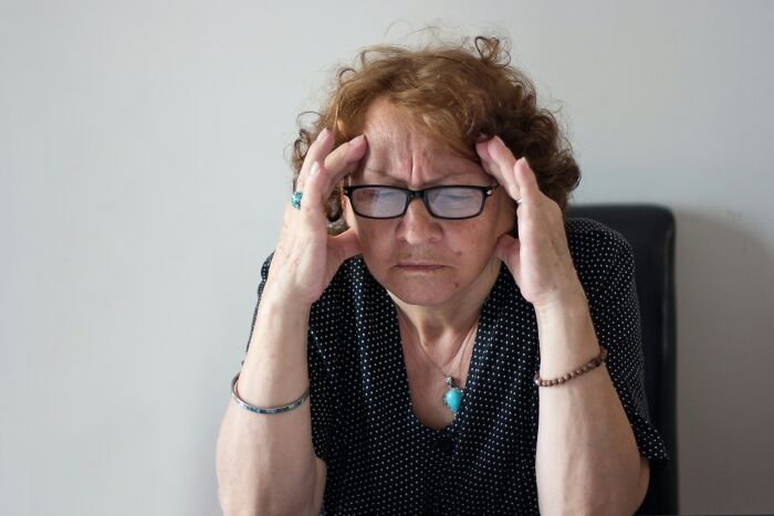 A distressed woman with hands on her temples, illustrating infuriating stories about MILs.