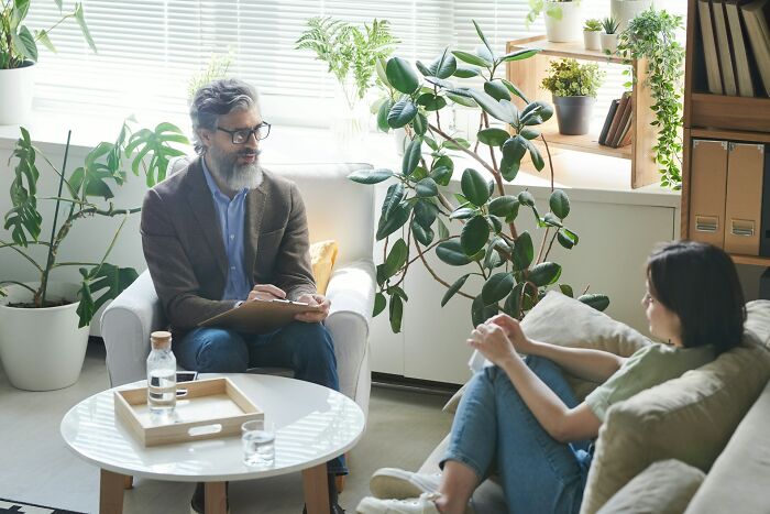 A therapist with a beard taking notes while a woman sits on a couch, depicting unhinged therapist moments.