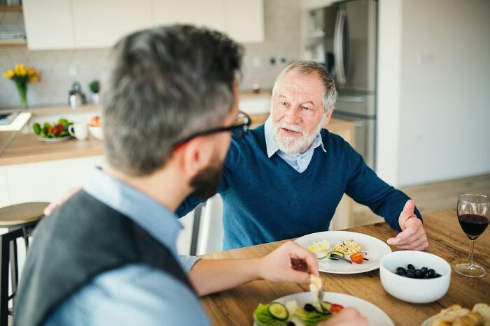 Two men, possibly an international partner and family, share a meal, discussing culture shocks and international partners.