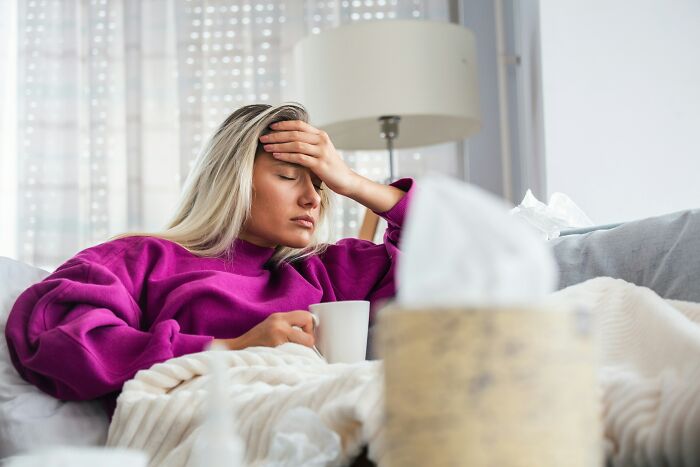 Woman with a headache holding a mug, experiencing moments of instant justice.