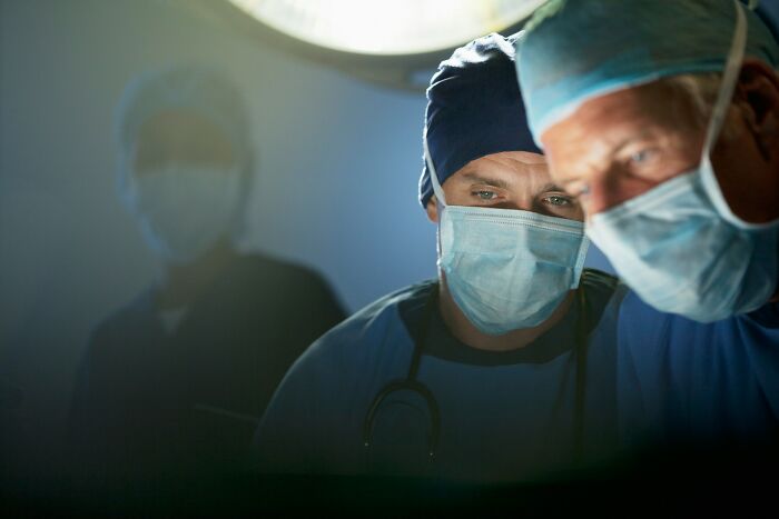 Two male surgeons in masks and scrubs focus intently, working to prevent medical mistakes.