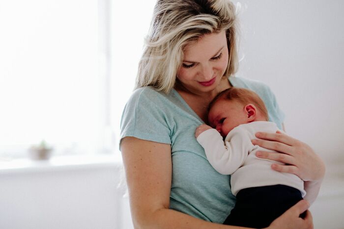 A tender moment of a mother holding her newborn, illustrating heartwarming babysitting stories.