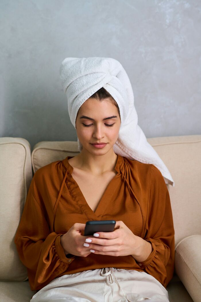 A woman with a towel on her head uses a phone, hinting at her changing mind about perfect guys.