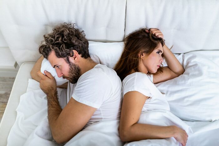 A divorced couple lies in bed, backs turned to each other, indicating the moment their marriage was over.