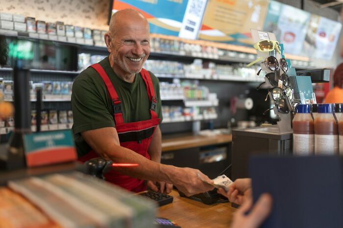 Smiling cashier handling money to a customer, a moment of instant justice.