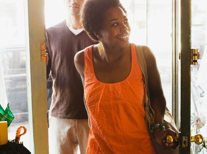 A woman smiling as she exits a doorway, symbolizing a need to leave a situation.