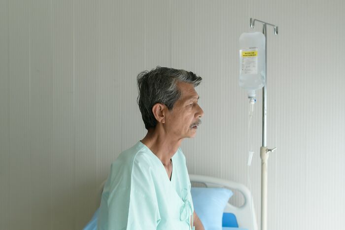 An elderly patient sits in a hospital bed with an IV drip, reflecting concerns about medical mistakes.