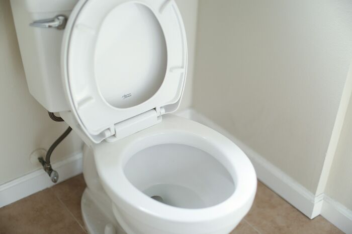 A white toilet with the seat up, highlighting American habits in a bathroom setting.