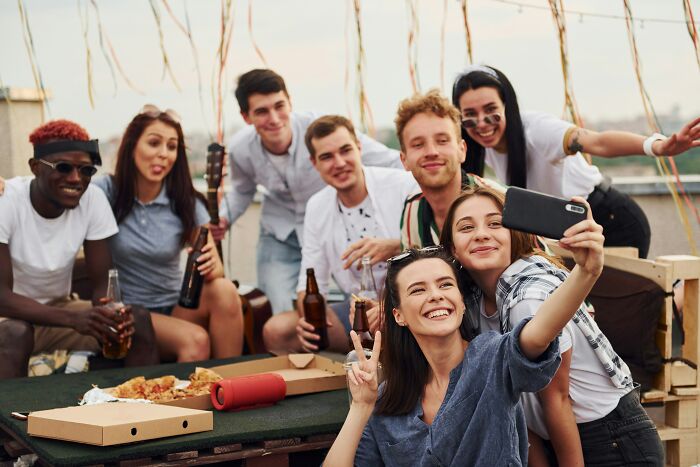 A group of friends happily taking a selfie on a rooftop, contrasting the painful ways men were made aware they were being cheated on.