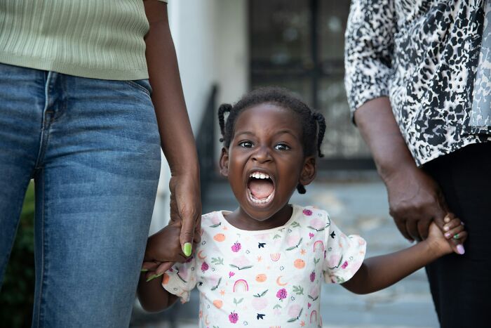 A little girl, whose expression shows how kids notice everything, holding hands with adults.