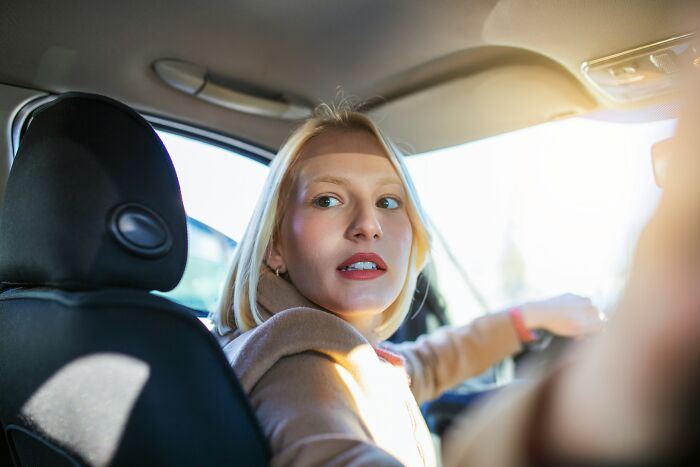 A woman looking suspiciously over her shoulder in a car, an indicator of being cheated on.