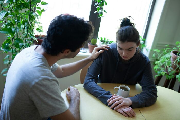 A man comforting a woman at a table, highlighting the painful ways men were made aware they were being cheated on.