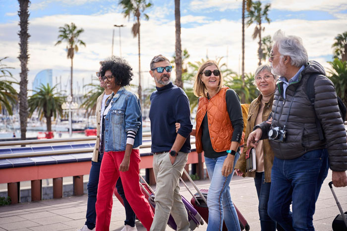 A group of diverse, happy tourists with luggage walking along a sunny waterfront, enjoying their tour. A group of diverse, happy tourists with luggage walking along a sunny waterfront, enjoying their tour.