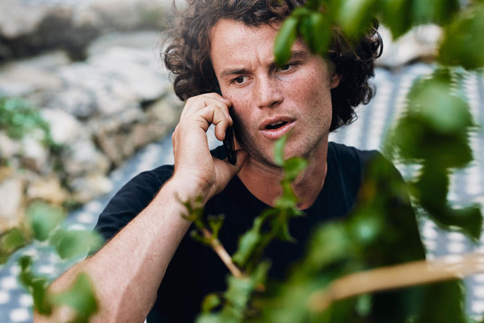 A man with curly hair talking on his cell phone, looking frustrated, potentially one of the entitled tourists. A man with curly hair talking on his cell phone, looking frustrated, potentially one of the entitled tourists.