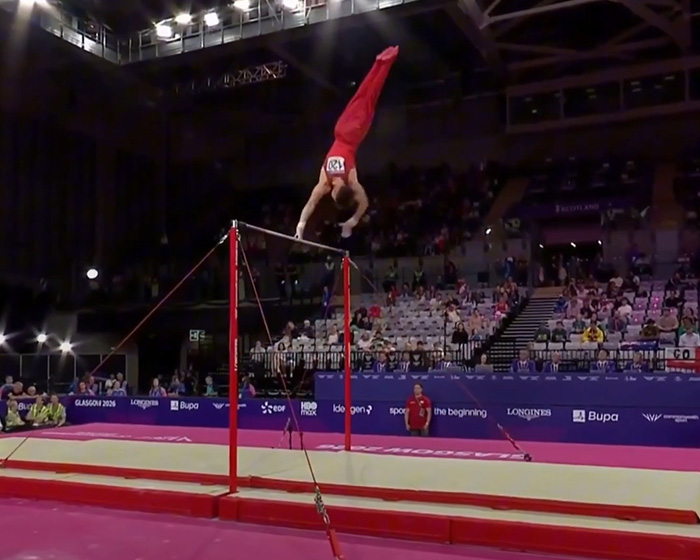 English gymnast mid-air after a horrific fall from the horizontal bar at the Commonwealth Games, an unfortunate moment.