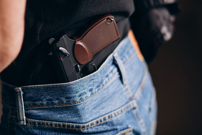 A pistol tucked into jeans, possibly a wedding guest making a regrettable choice.