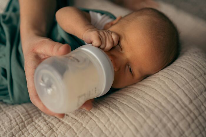 A parent bottle-feeding a newborn baby, reflecting stories about MILs.