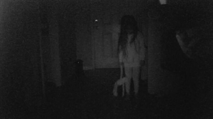 A grainy, dark image of a child in a hallway, holding a doll, making parents terrified.