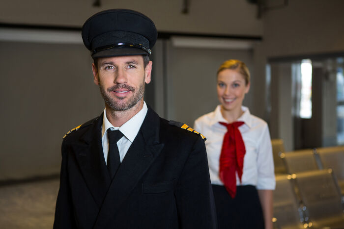 A pilot and a flight attendant, jobs guys have that make women swipe left, smile in an airport.
