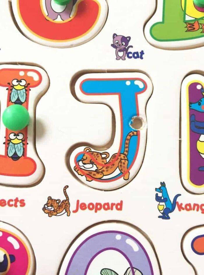 A wooden alphabet puzzle where the letter 'J' is incorrectly associated with 'Jeopard' instead of 'Jaguar', a designer's fail.