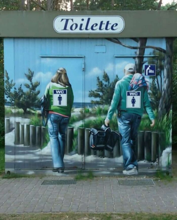 A public toilet with murals of people walking away, and gender signs misplaced, showcasing designers' mistakes.