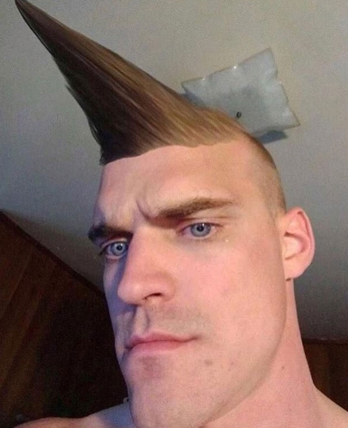 A man with a severely spiked mohawk and shaved sides, looking intensely at the camera. This is an example of bad hair mistakes.