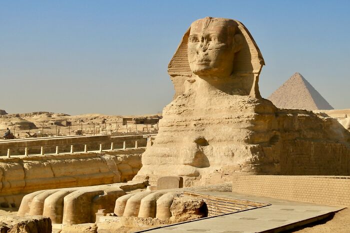 The Great Sphinx of Giza with a pyramid in the background, an iconic unsolved mystery.