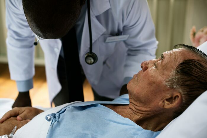 A doctor attends to an elderly patient in a hospital bed, a common setting for hospital horror stories.
