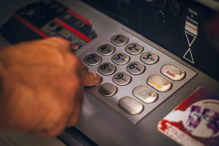 A hand entering a PIN on an ATM, representing the unsettling reality of hospital employees' horror stories.