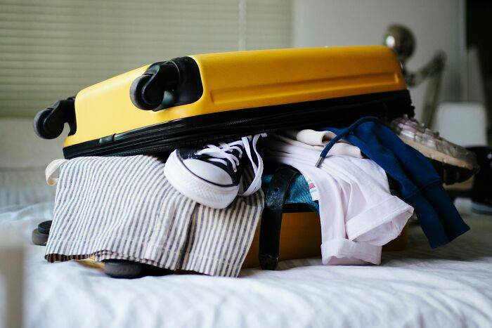 Overstuffed yellow suitcase with clothes and shoes, important for hotel industry secrets and vacation.