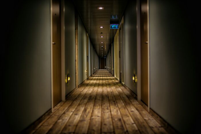 Long dark hotel hallway with warm lights, hinting at hotel industry secrets for your vacation.