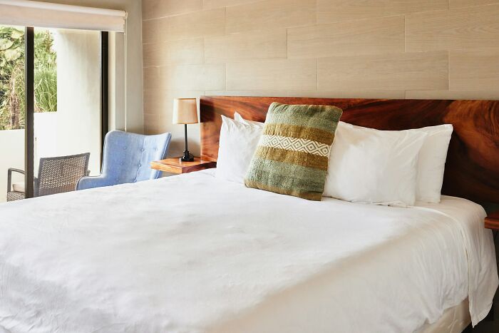 A clean, modern hotel room with a comfortable bed, revealing helpful hotel industry secrets for your next vacation.