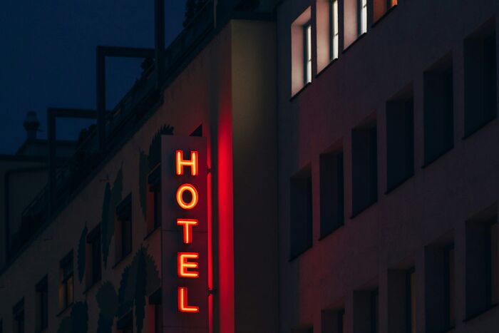 A glowing red Hotel sign at night, revealing helpful hotel industry secrets before your next vacation.