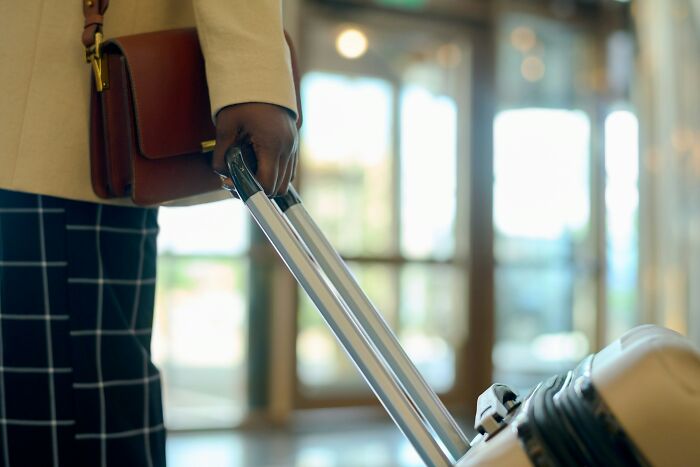 A person pulling a suitcase, ready for a vacation, with hotel industry secrets to consider.