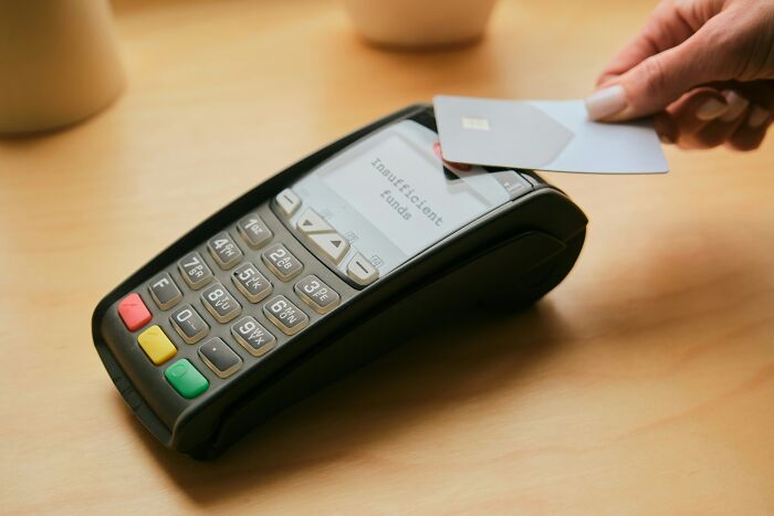 A hand holding a credit card over a payment terminal displaying insufficient funds. Learn hotel industry secrets for your next vacation.