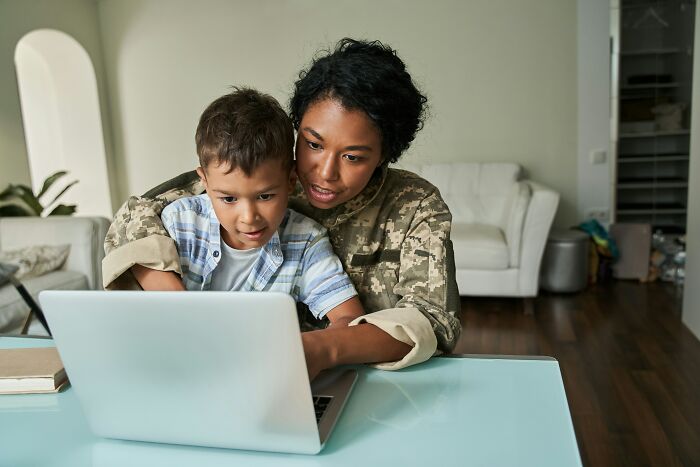 Woman in uniform and child looking at a laptop, revealing helpful hotel industry secrets for your next vacation.