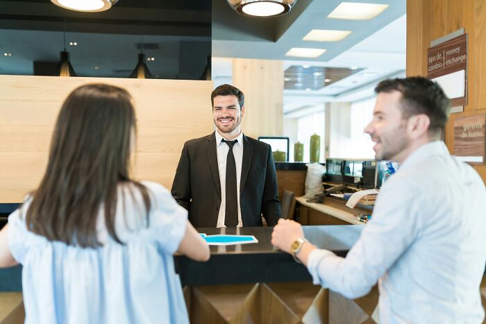 Guests checking in at a hotel front desk, learning hotel industry secrets for their vacation.