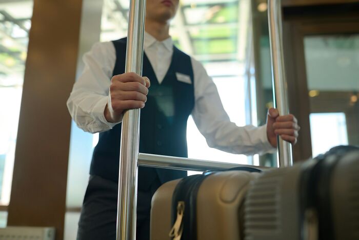 A hotel bellhop pushes a luggage cart, revealing useful hotel industry secrets for your next vacation.