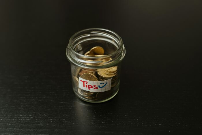 A glass jar labeled Tips filled with coins, revealing hotel industry secrets about service on vacation.