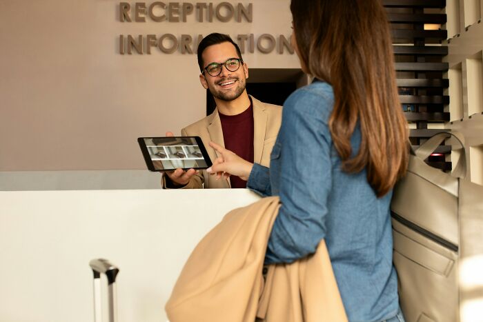 A hotel receptionist warmly greets a guest, illustrating helpful hotel industry secrets for a smooth vacation.