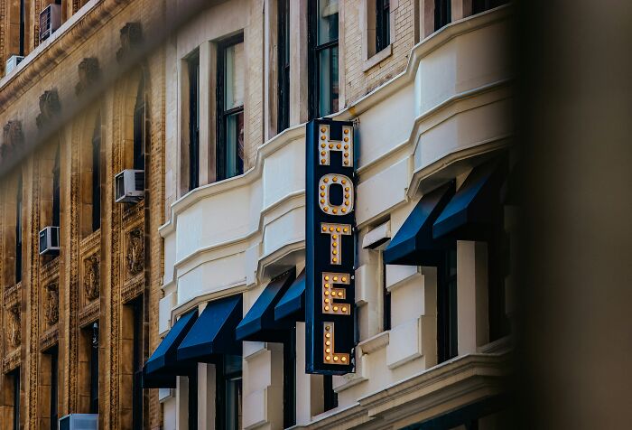 A vintage HOTEL sign illuminates an elegant building, hinting at hotel industry secrets for a perfect vacation.