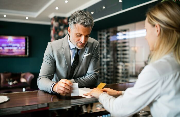 Man checking in at a hotel reception, learning helpful hotel industry secrets for a better vacation.