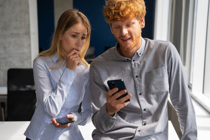 A couple looking worried and stressed while looking at a phone, after their house sitter crashed car and lost cat.