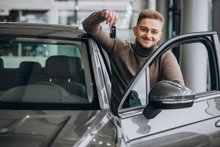 Smiling house sitter holding car keys, leading to a crashed car incident.
