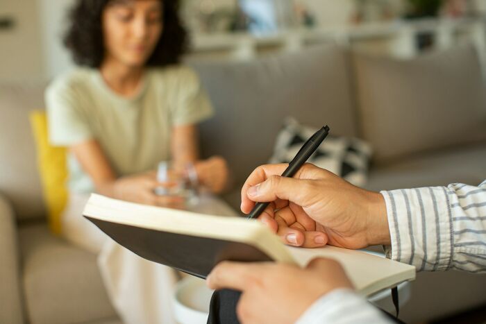 A therapist taking notes while a patient is blurred in the background, discussing unhinged therapist moments.