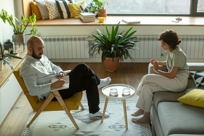 A man and a woman in a therapy session, discussing infuriating mansplaining examples in conversation.
