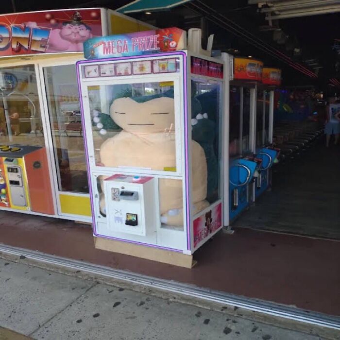 A giant Snorlax plush toy trapped inside a claw machine at an arcade, a surprising No Context Humans meme.