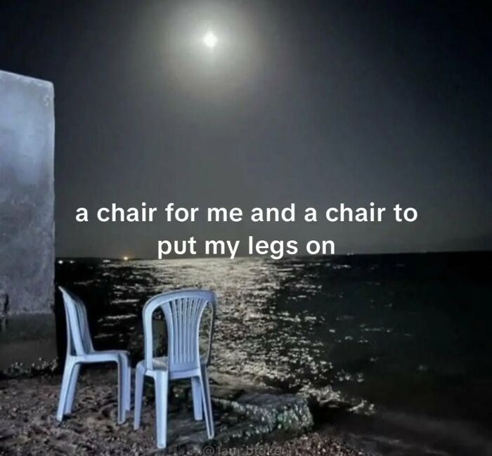 Moonlit beach scene with two chairs, captioned a chair for me and a chair to put my legs on, entertaining memes.
