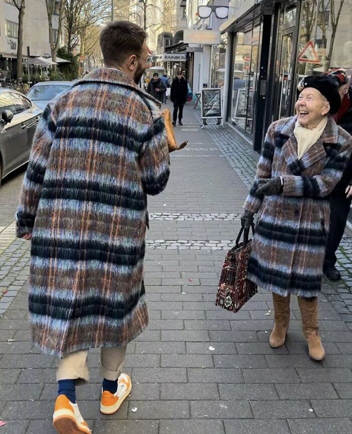 An older woman and a man in matching plaid coats on a street, a heartwarming photo among funny No Context Humans memes.